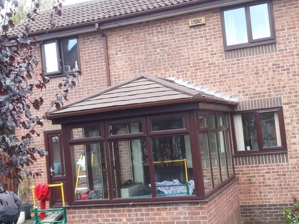 Conservatory with a tiled warm roof and rosewood frames